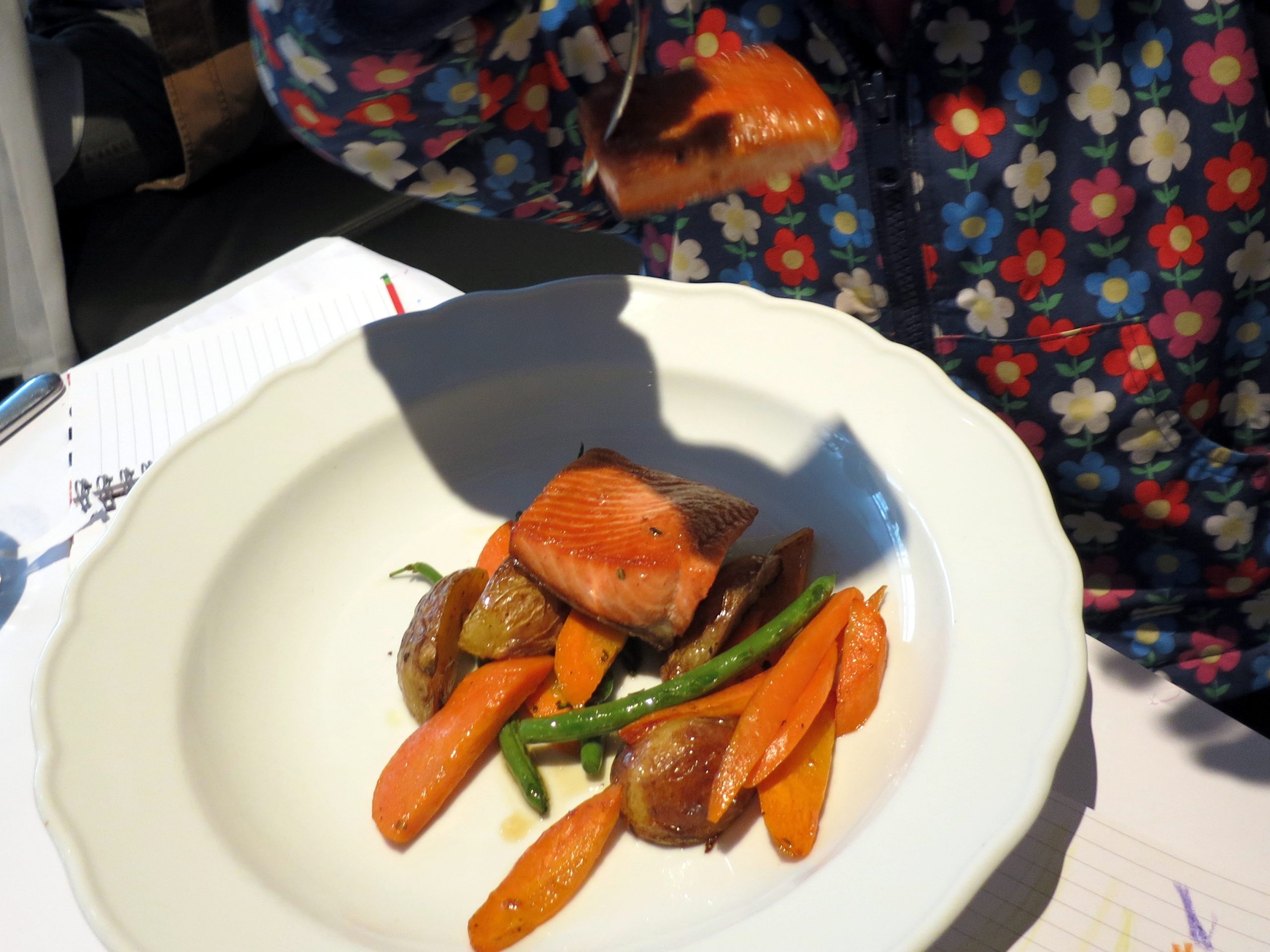 A children's restaurant meal of salmon with roast potatoes, carrots and green beans in a white bowl