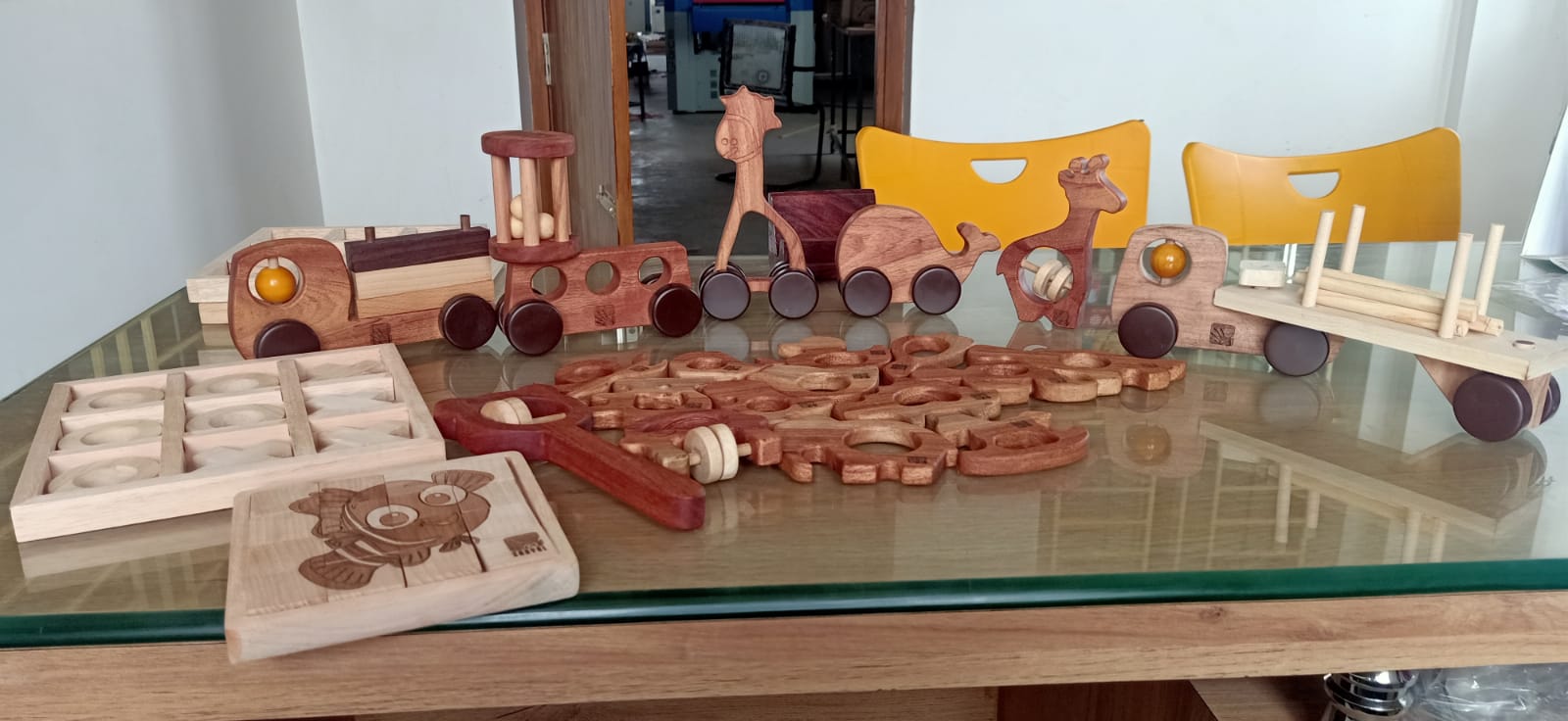 A table covered with handmade wooden toys including trucks, animals and simple puzzles