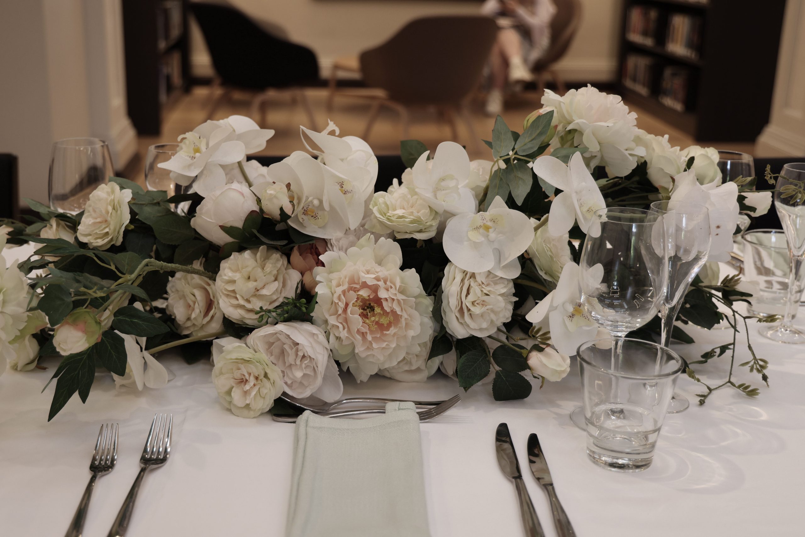 Table laid with white flowers, glasses and cutlery for a special occasion dinner