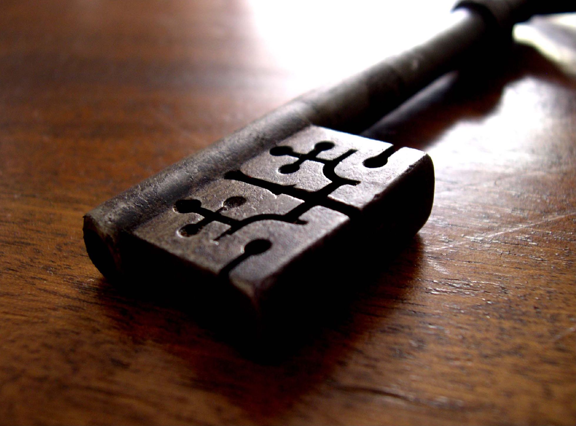 Close-up of an old iron key lying on a polished wooden table