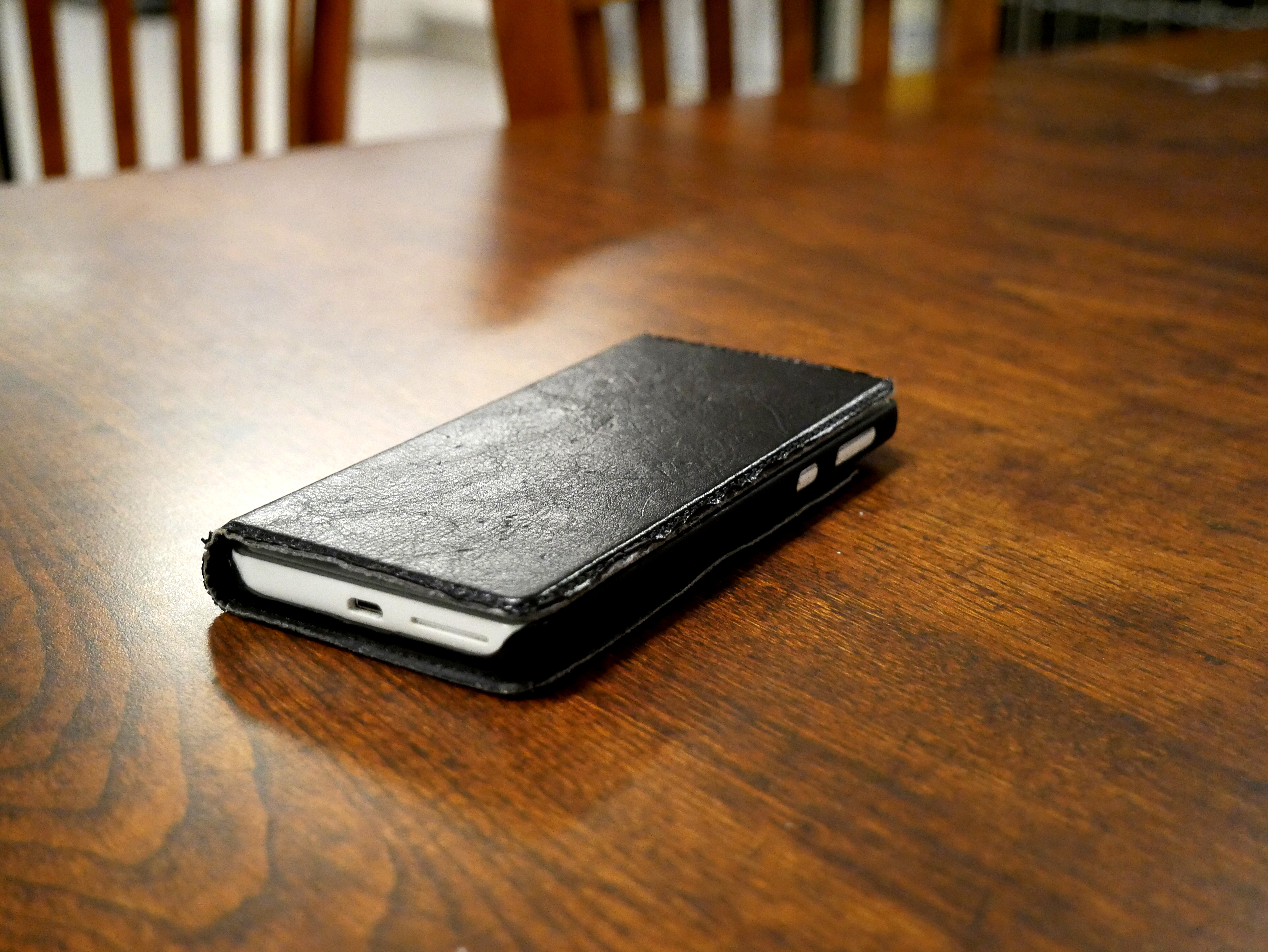 Phone in a closed case resting face down on a wooden dining table