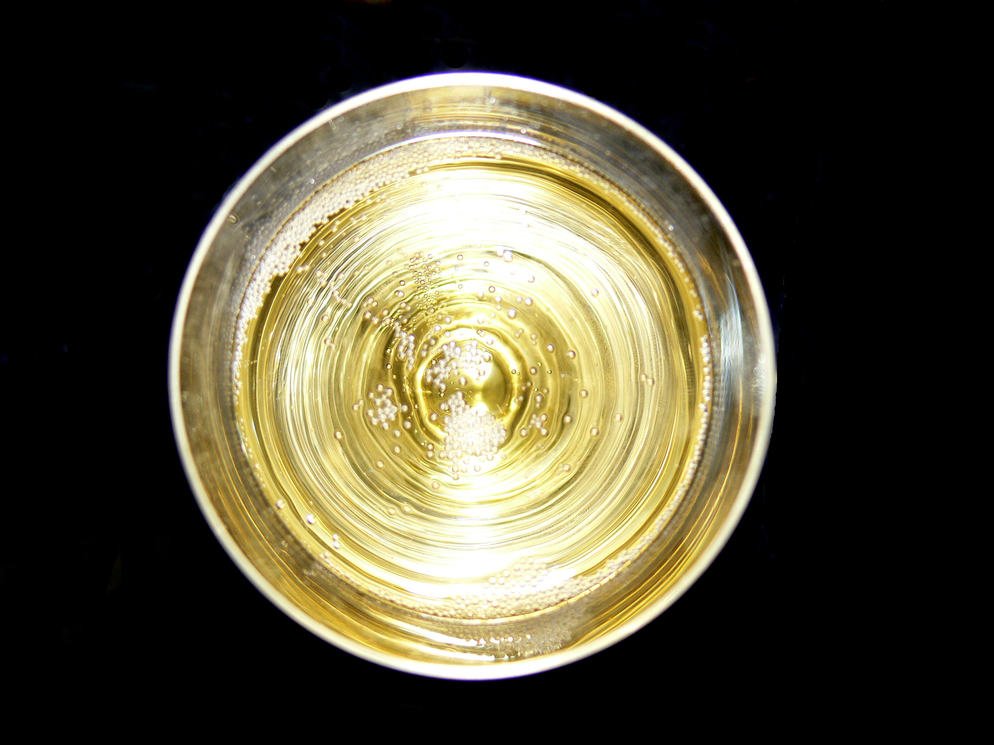Overhead view into a glass of sparkling wine with bubbles around the rim