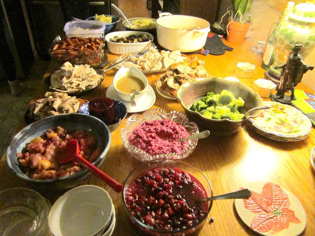 Potluck-style Thanksgiving spread of side dishes, cranberry sauce and salads on a wooden table